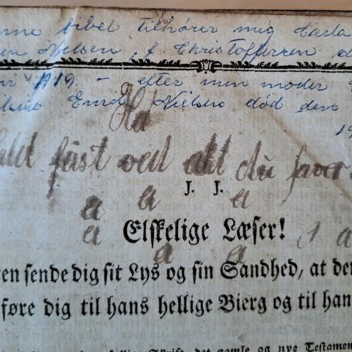 Farvefoto af side i bog med indskrift i kuglepen.